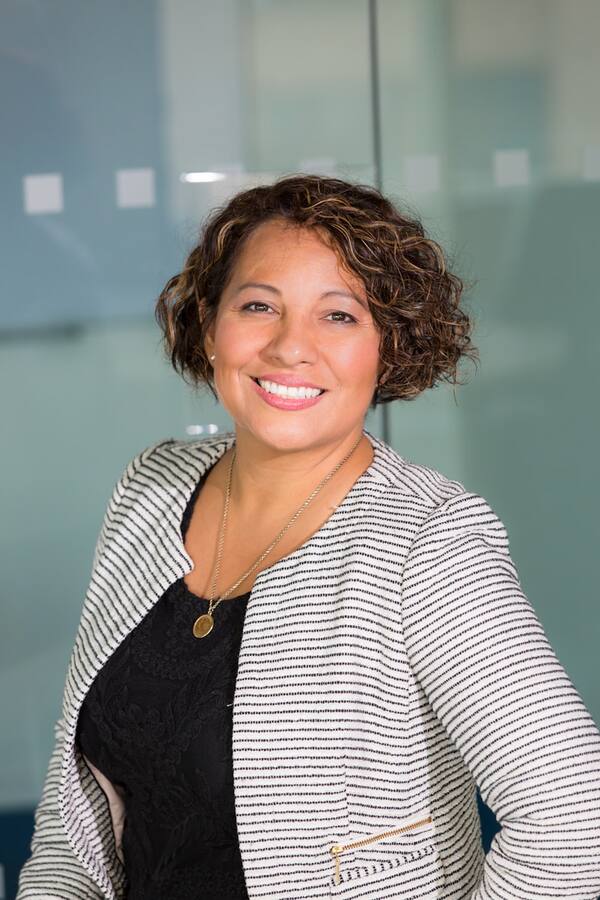 Sarah smiling in a striped blazer.